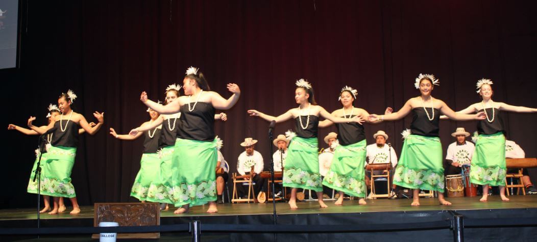 Females in traditional Cook Island dress performing a dance on stage